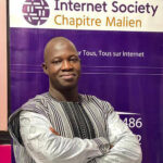 un homme avec les bras croisés, devant une bannière du Chapitre du Mali de l’Internet Society