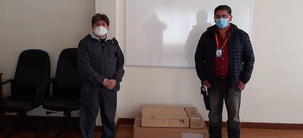 Two men with masks standing next to carton packages.
