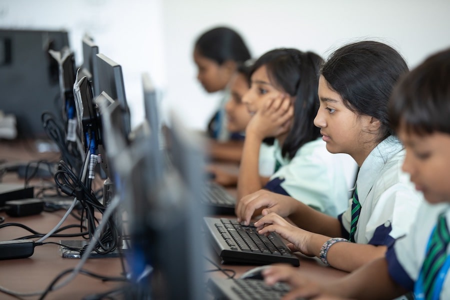 Children in classroom in front of computers. 