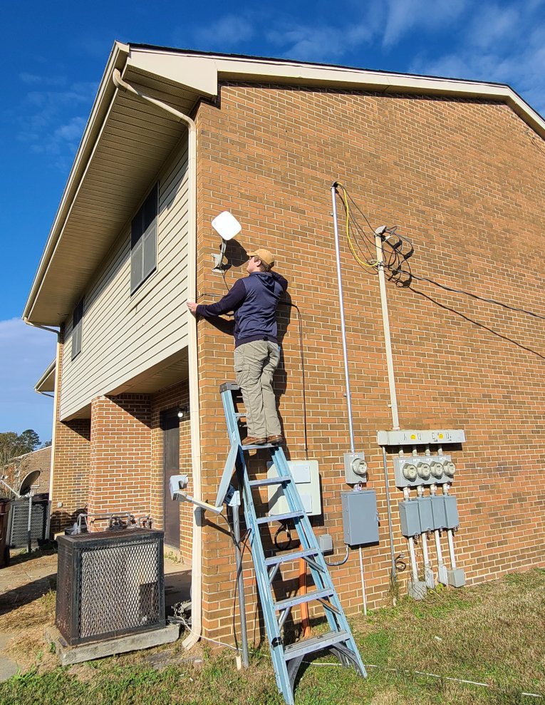 a man on a ladder installing an antenna	