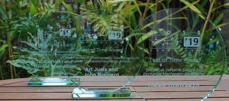 Three transparent glass award plaques on a table