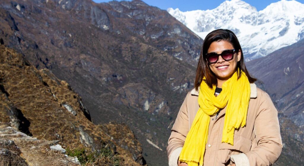 a woman smiling at camera in front of mountain peak